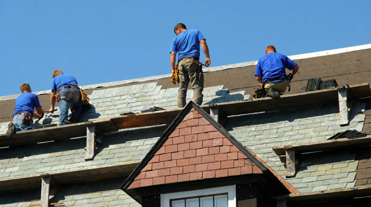 Roof replacement in progress with a team of professional contractors installing new shingles on a residential home in Lowell, MA